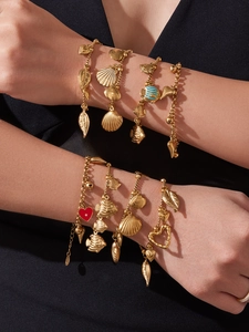 Close-up of gold stainless steel bracelet featuring sea shell and starfish charms on a wrist