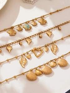 Detail of four golden summer beach bracelets with shell, fish, and leaf charms