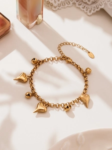 Detailed macro view of gold-plated stainless steel heart charms and bells on a chain