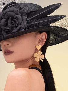 Detail of matte gold four-leaf clover earrings and matching necklace set on model