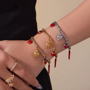 Set of 18k gold plated stainless steel bracelets with sun and chili charms on a model