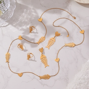 18k gold plated stainless steel fishbone and heart jewelry set on marble background