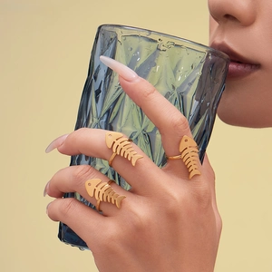 Golden fishbone rings set for women in stainless steel worn by a model with a glass