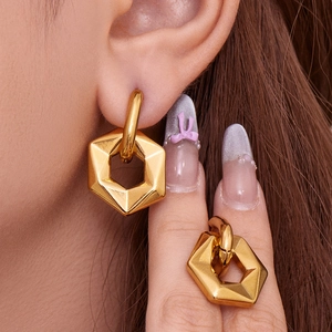 Minimalist gold geometric hexagonal hoop earrings worn by a model in a close-up shot