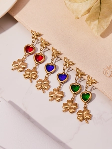 Detailed shot of gold heart earrings with butterfly studs in red blue and green gems