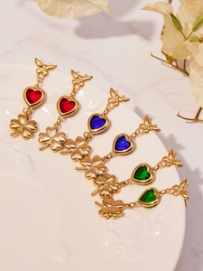 Detail of butterfly and heart drop earrings with colorful zircon stones on ceramic