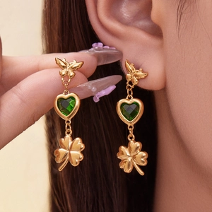 Golden butterfly earrings with green heart zircon and clover charms on model