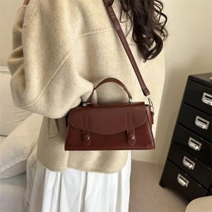 Vintage brown leather crossbody bag styled with a beige coat and white skirt