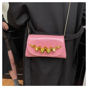Détail d'un sac à bandoulière rose en cuir verni avec boucle en métal doré ondulé