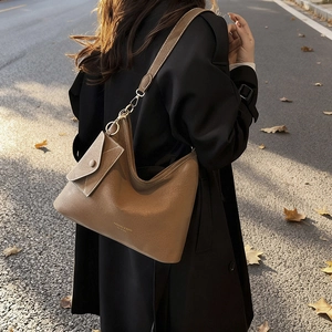 Brown leather tote bag with matching pouch shown in warm autumn sunset city street