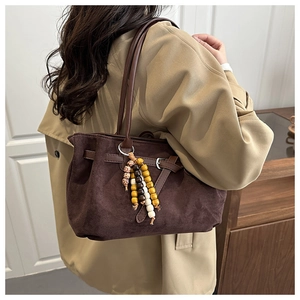 Detailed view of brown suede tote bag featuring retro multi-color beads and buckle strap