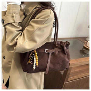 Close-up of brown suede tote bag with leather belt buckle and vintage wood bead tassel