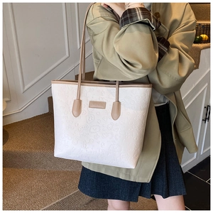 Detail of embossed large tote bag with cream leather and brown straps on a model