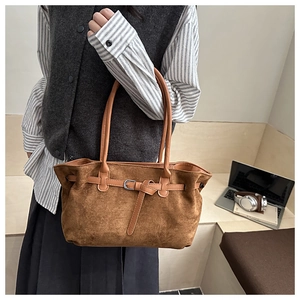 Close-up of brown suede tote bag with leather straps and silver buckle detail