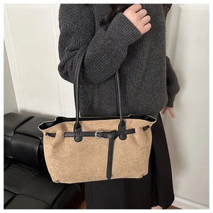 Close-up of retro suede tote bag featuring camel body with black strap and buckle detail