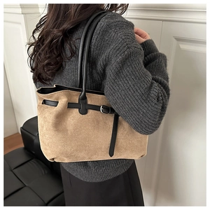 Detail of tan suede tote bag featuring black leather straps and silver metal hardware