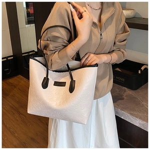 Close-up of cream embossed tote bag with cartoon patterns and black contrast handles