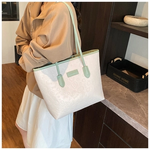 Detail of mint green strap and cream faux leather tote with embossed cartoon pattern