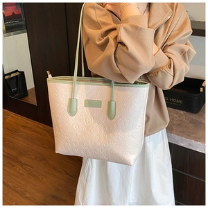 Detail of pink tote bag with cartoon embossing and mint green handles on a model