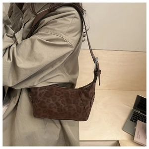 Gros plan du sac hobo à imprimé léopard avec texture daim sur un mannequin en trench-coat