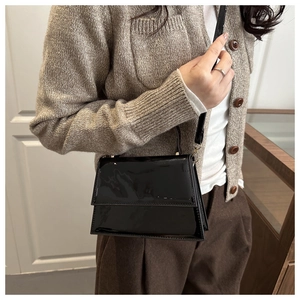 Glossy black patent leather mini square bag with crossbody strap shown on a model