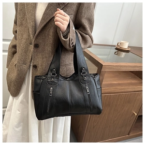 Detail of black faux leather tote bag with dual decorative vertical zippers and wide strap