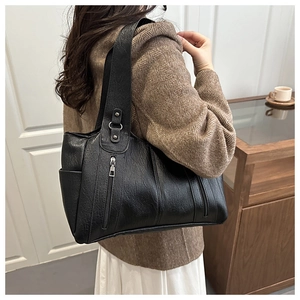 Close-up of black lychee-textured tote bag with vertical zipper on model shoulder