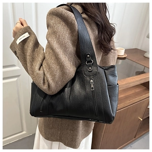 Macro detail of a black vintage leather tote bag with stylish zipper pocket and strap