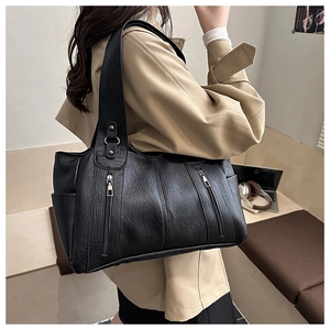 Detail of black pebbled leather tote bag with dual zippers worn with a stylish trench coat