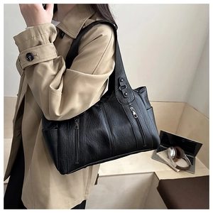 Detail of a large black leather tote bag with zip pockets and a wide shoulder strap