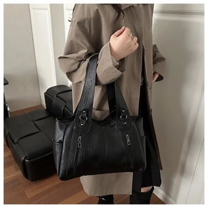 Close-up of retro pleated leather tote bag with stylish vertical metal zipper pockets