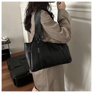 Detail view of black leather tote bag with lychee texture and vertical zip pockets