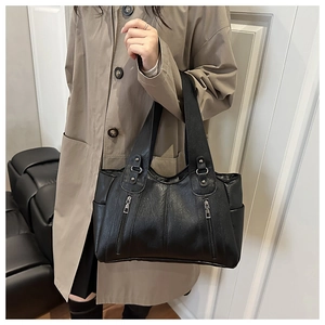 Detail of black tote bag featuring pebbled faux leather and vertical zipper accents on shoulder