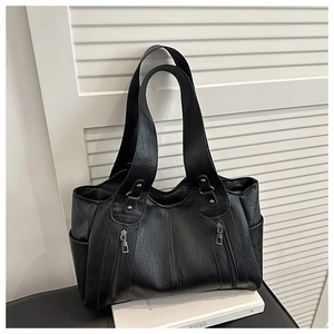 Detail view of large black leather tote bag with dual shoulder straps and side pockets