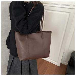 Dettaglio di una borsa tote in pelle martellata marrone scuro con logo inciso minimalista