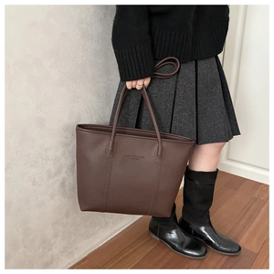 Close-up of brown litchi pattern leather tote bag featuring fashion embossed lettering