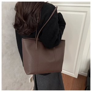 Close-up of brown pebbled leather tote bag showing fine texture and long shoulder straps