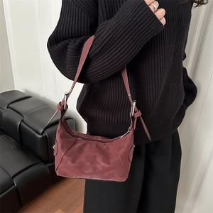 Sac sous le bras demi-lune bordeaux chic avec détails argentés porté par un mannequin