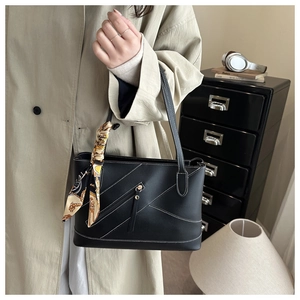 Detail of black tote bag with white contrast stitching and printed silk scarf handle