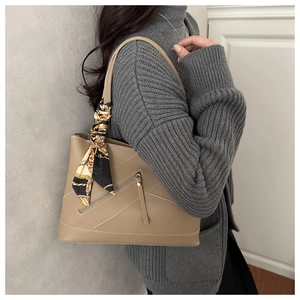 Detail of beige tote bag featuring diagonal stitching and decorative silk scarf handle