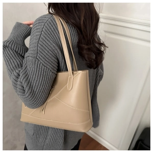 Detail of beige large tote bag with contrast stitching and leather tassel accessory