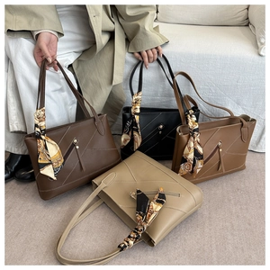Detail of four chic tote bags in various colors with geometric stitching and silk scarves