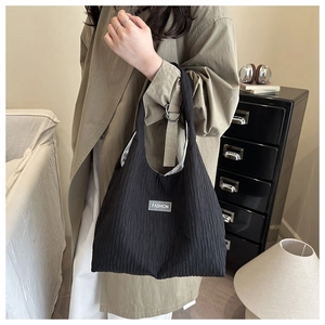 Close-up of black striped tote bag with Fashion label carried by a model in trench coat