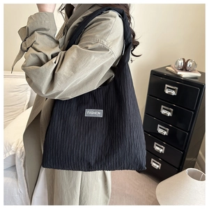 Detail of black tote bag featuring crinkled texture fabric and minimalist Fashion label