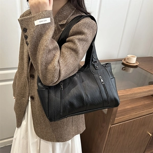 Minimalist black PU leather tote bag with dual zippers worn by a model in office style