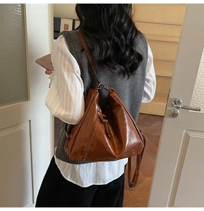 Detailed view of brown vintage hobo bag with glossy leather and wrinkled texture on model