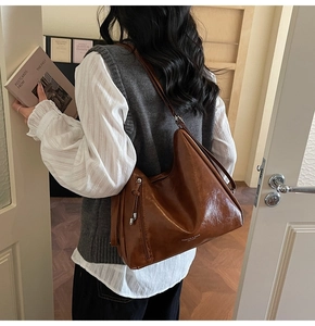 Detail of vintage brown oil wax leather tote bag with wide strap and gold lettering