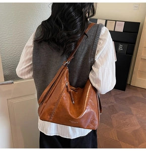 Detail view of large vintage brown leather hobo bag with side zipper and embossed logo