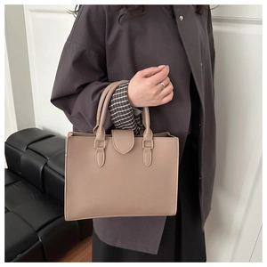 Detail view of the beige leather tote bag featuring sleek handles and structured side profile