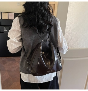 Macro shot of dark coffee shiny leather bag with silver zippers on a model's shoulder